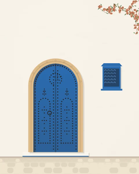 A bright blue arched door on a white wall, its leaves patterned in black nail heads, with a carved stone frame, a blue window box and bougainvillea.