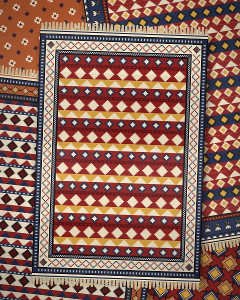 A pile of flatwoven kilims in madder and indigo, banded with triangles and diamonds, over a madder rug of stars and a rust rug of small crosses.