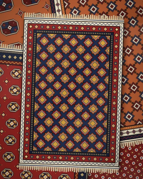 A pile of rugs on a dark floor, an indigo rug of eight-pointed stars with a rosette border on top, over madder and rust rugs of guls and latch hooks.