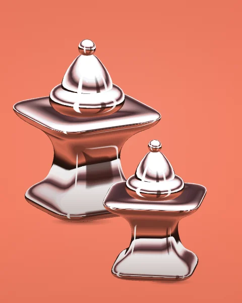 Two chrome incense burners, one turned to the side, stand together on a coral ground.