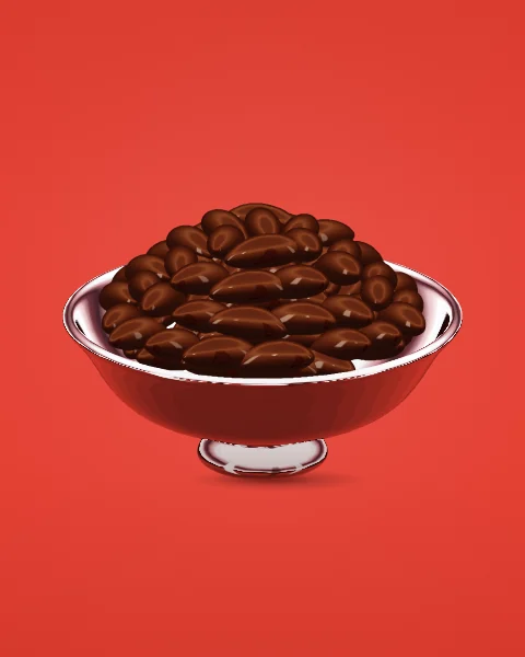 A footed chrome bowl heaped with glossy brown dates, seen from slightly above on a tomato red ground.