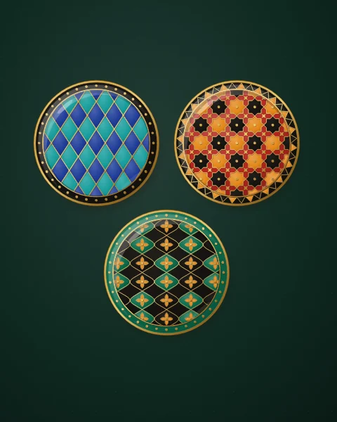 Three enamel plates in cobalt, carnelian and black, patterned with a diamond lattice, a field of eight-pointed stars and an ogival net, on deep forest green.