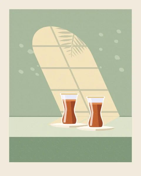 Two glasses of amber tea on their saucers stand on a pale table in a patch of sun shaped like a round-arched window. The shadow of a palm frond falls across the light on the sage-green wall.
