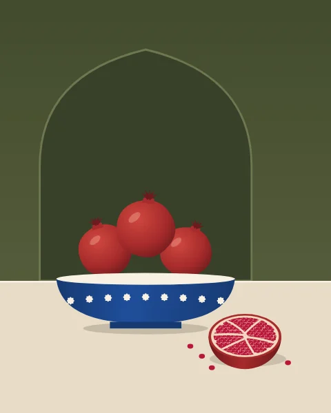 Three ripe pomegranates, each with its pointed crown, heaped in a shallow cobalt bowl banded with white stars, on a pale table against a deep olive wall; upright formats set the bowl before a shallow arched niche. In front lies a halved fruit, its seeds packed between pale membranes, with a few loose seeds beside it.