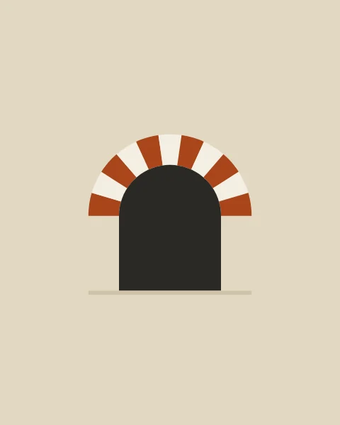 A round arch over a dark opening on a cream wall, its ring made of wedge-shaped stones in alternating clay and cream.