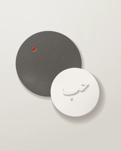 Two overlapping discs, charcoal concrete behind and white plaster in front, the word hubb raised in Nastaliq on the plaster, with a red glazed dot.