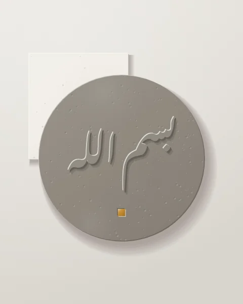 A large warm grey concrete disc with bismillah raised in Nastaliq, an ochre tile beneath it and a plaster slab behind.