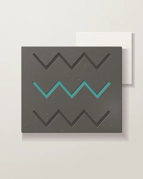 A charcoal concrete panel cut with stacked zigzag grooves, the middle one laid in turquoise glaze, in front of a pale plaster slab.