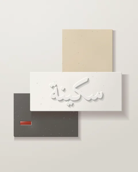 A white plaster panel with sakina raised in Naskh script, overlapping a sand slab above and a charcoal concrete slab below with a red glazed bar.