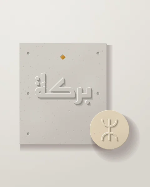 A concrete panel with baraka raised in Kufic and an ochre lozenge above it, joined by a small sand disc carved with the Amazigh aza.
