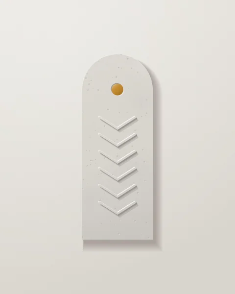 A slim concrete stele with a rounded top, carved with a column of chevrons beneath an ochre glazed disc.