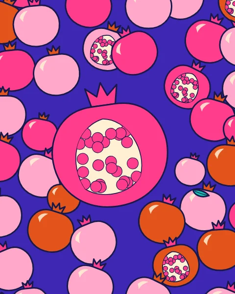 A heap of pomegranates fills the frame, with one large fruit split open to show its seeds.