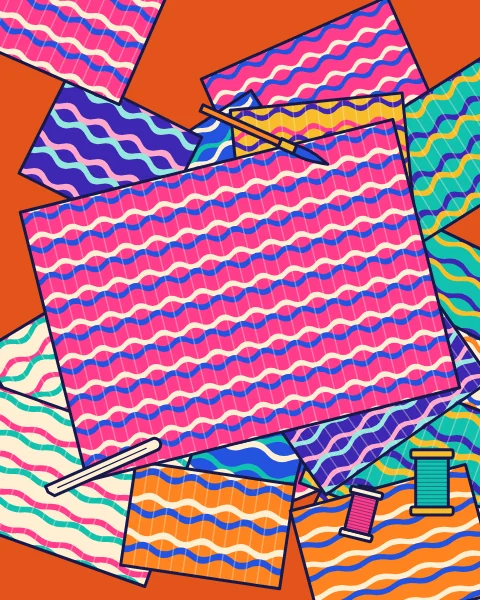 Sheets of marbled paper in wave patterns overlap across a table, with a folder, a brush and spools of thread.
