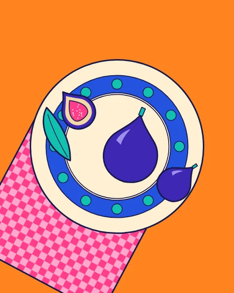Two figs, a halved fig and a leaf on a patterned plate, set on a pink check napkin.