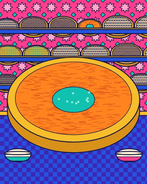A large tray of kunafa with pistachios on a blue counter, with shelves of sweet trays behind.