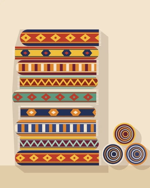 A tall stack of folded flatweave rugs, each edge showing a different stripe, diamond or zigzag, with rolled rugs beside it.
