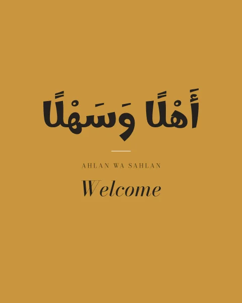 Ahlan wa sahlan in rounded black lettering on ochre, with a short rule, its transliteration and “Welcome” in italic serif beneath.