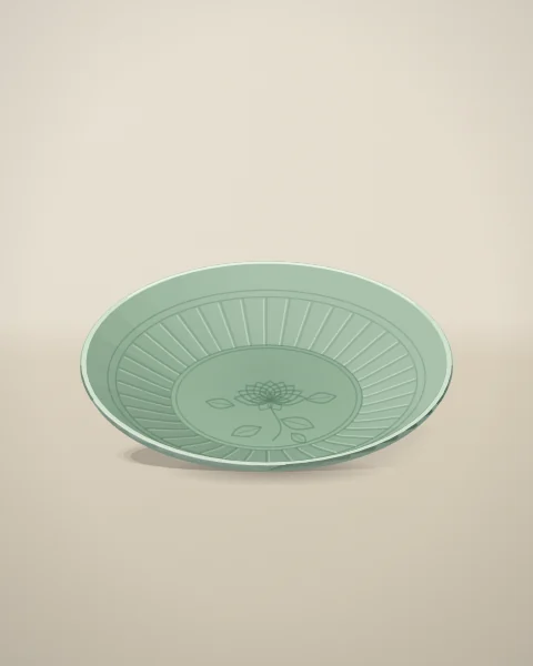 A wide sea-green dish with a fluted well and a softly incised peony at its centre, resting on linen.